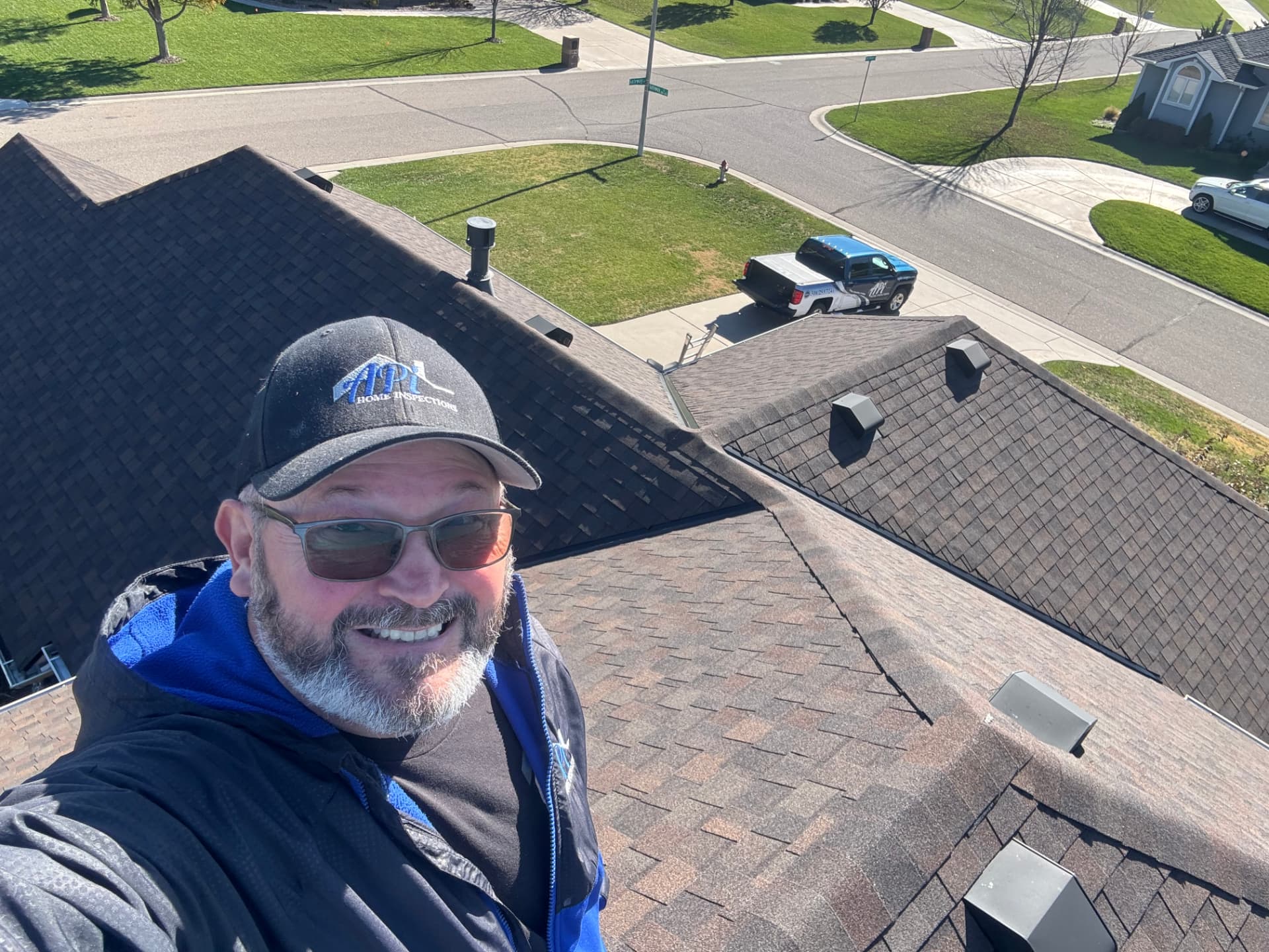 API Home Inspections inspector on a roof with the company truck parked below